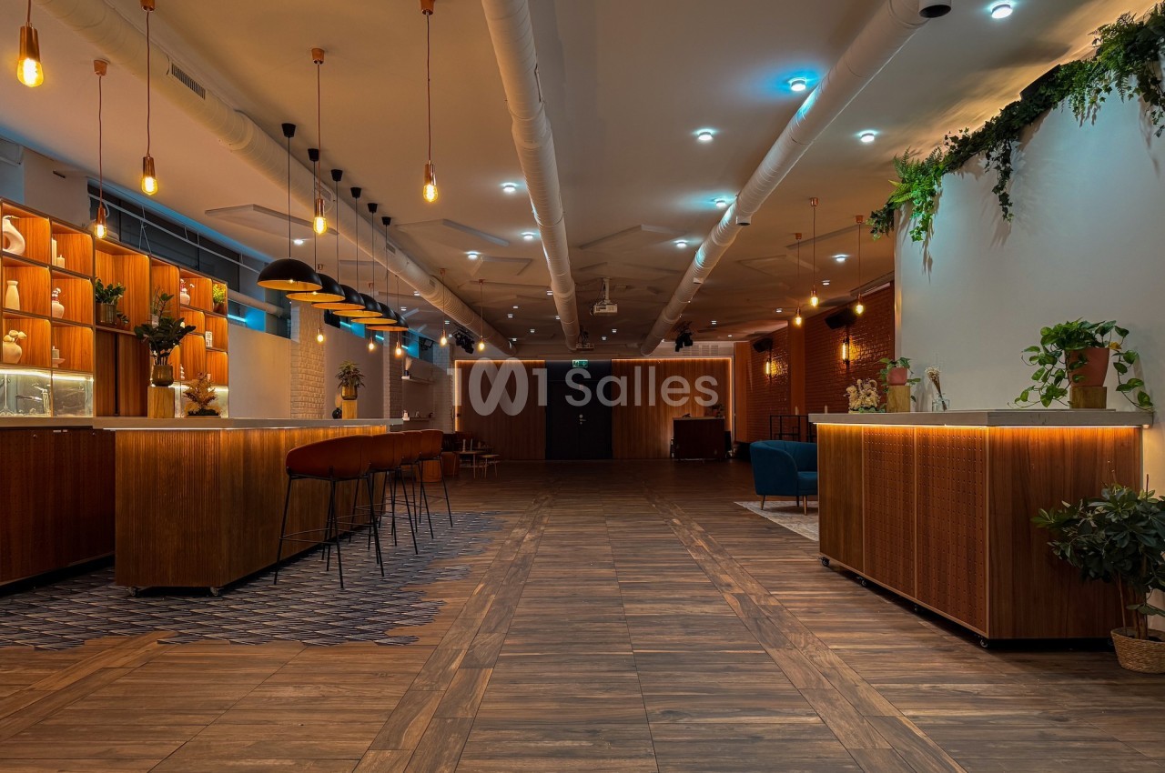 Espace intérieur moderne avec comptoirs en bois, éclairage suspendu et plantes décoratives.