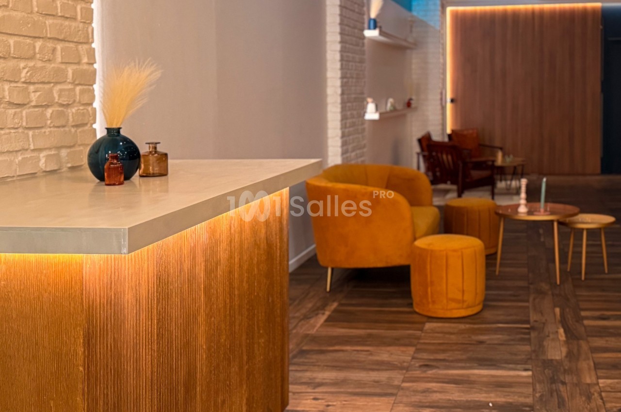 Espace intérieur chaleureux avec mobilier en velours orange, comptoir en bois clair et éclairage tamisé.