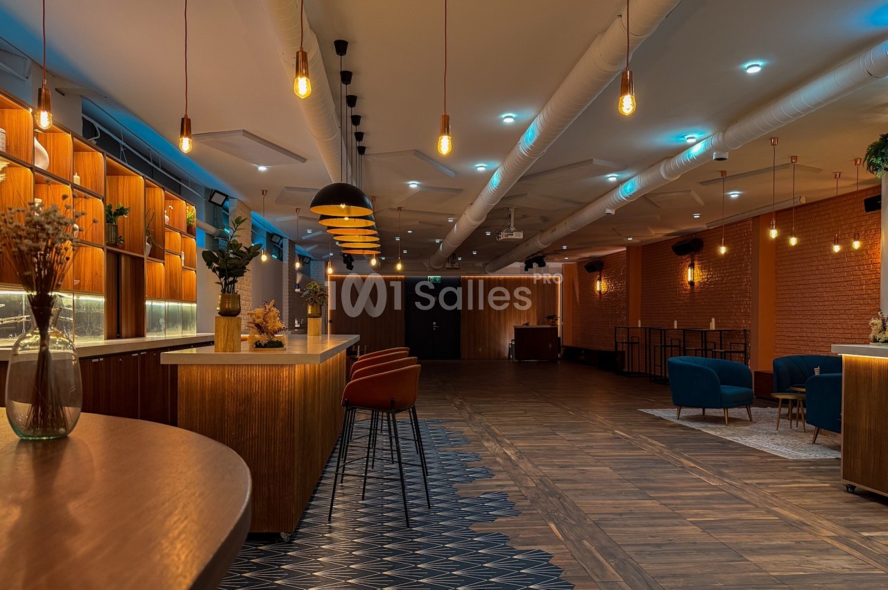 Salle moderne avec éclairage chaleureux, mobilier en bois, chaises colorées et décorations minimalistes.
