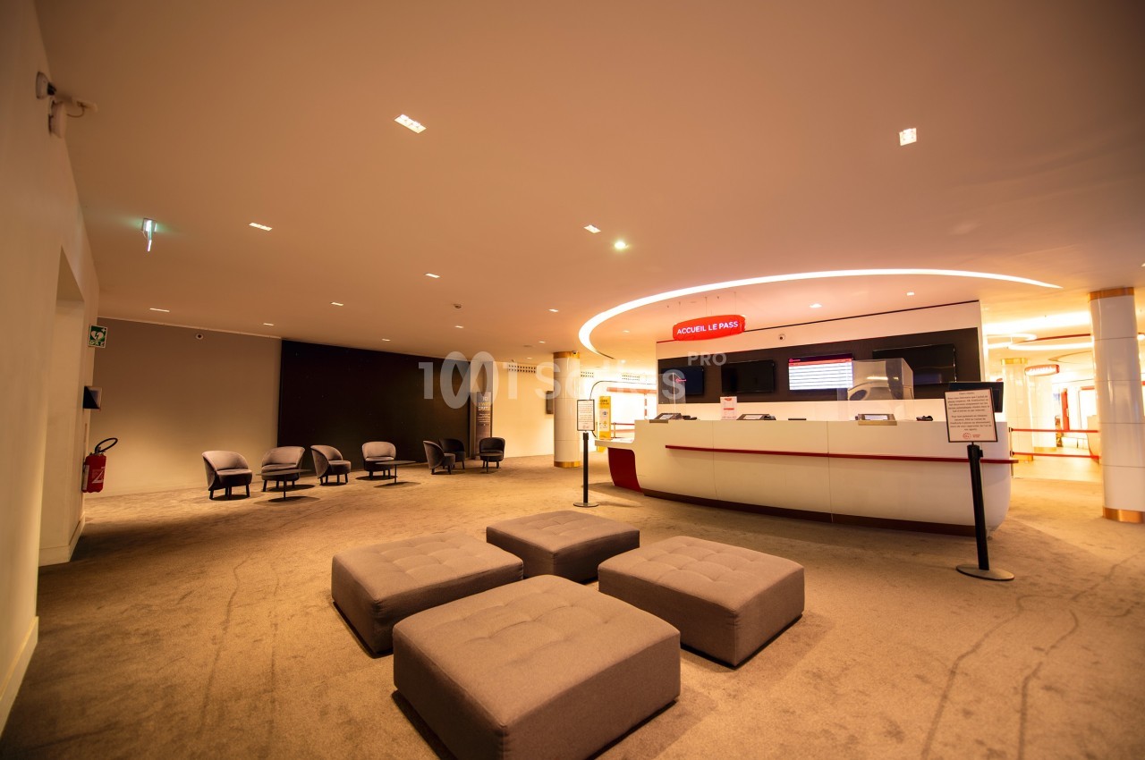 Espace d'accueil moderne avec comptoir blanc, sièges rembourrés et éclairage chaleureux.