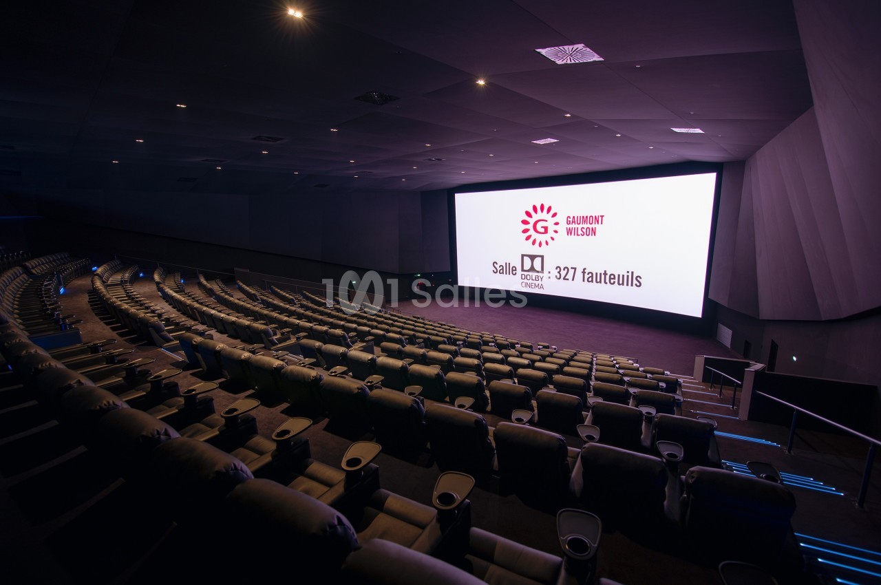 Salle de cinéma moderne avec grands fauteuils inclinables et écran géant affichant des informations sur la capacité.
