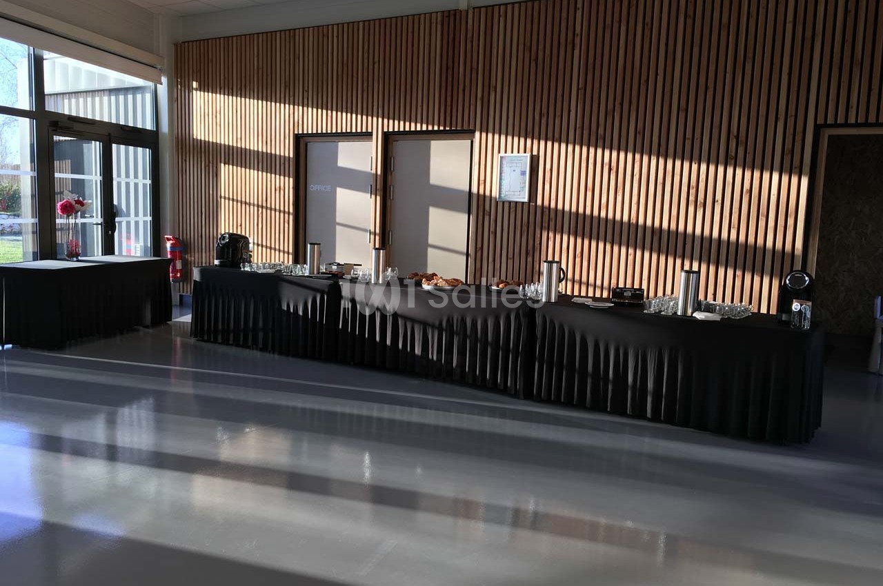 Table de buffet noir dressée dans une salle lumineuse avec des murs en bois et des portes fermées en arrière-plan.