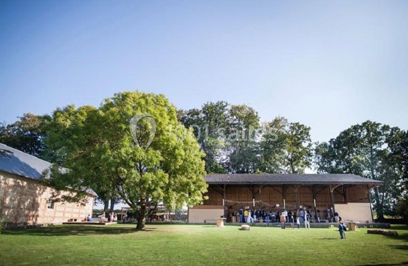 Un bâtiment en bois entouré d'arbres avec des personnes rassemblées sur une pelouse par une journée ensoleillée.