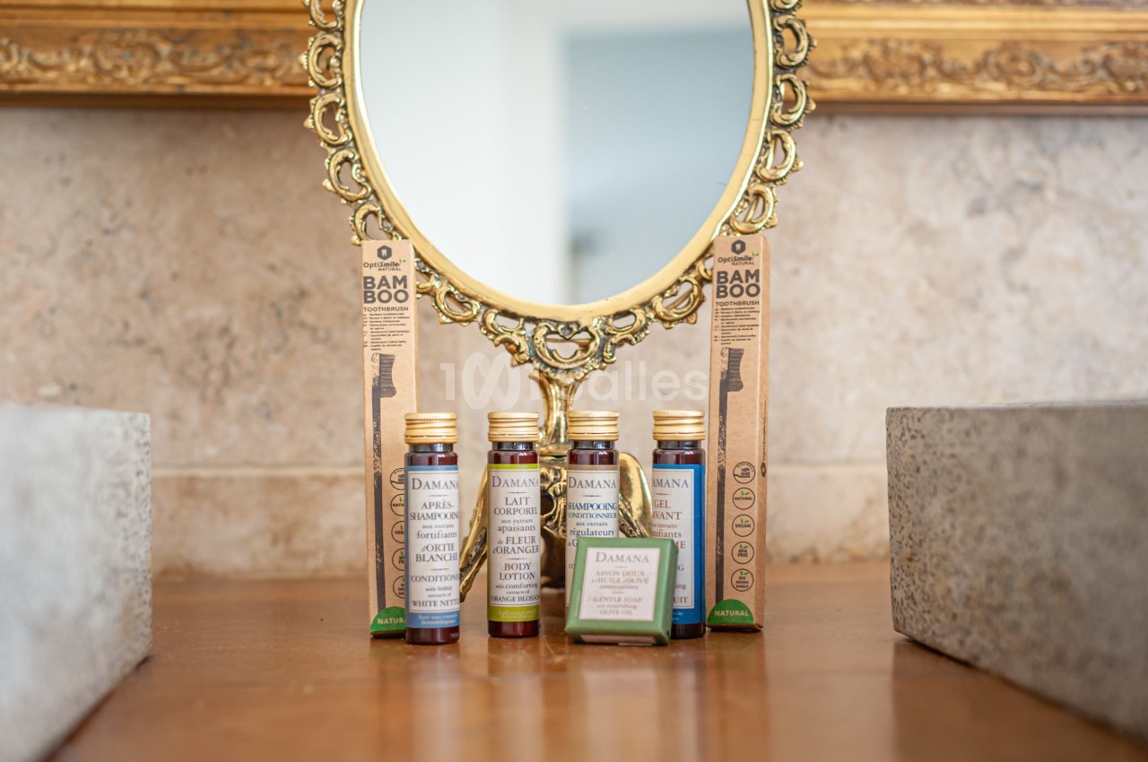 Produits de soins et brosses à dents en bambou disposés devant un miroir doré sur une surface en bois.