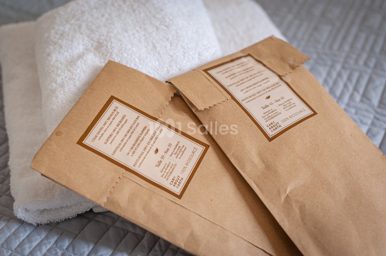 Deux sachets en papier kraft posés sur une serviette blanche, sur une couverture matelassée grise.