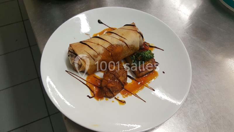 Assiette contenant un rouleau croustillant, une garniture de légumes et une sauce décorative.