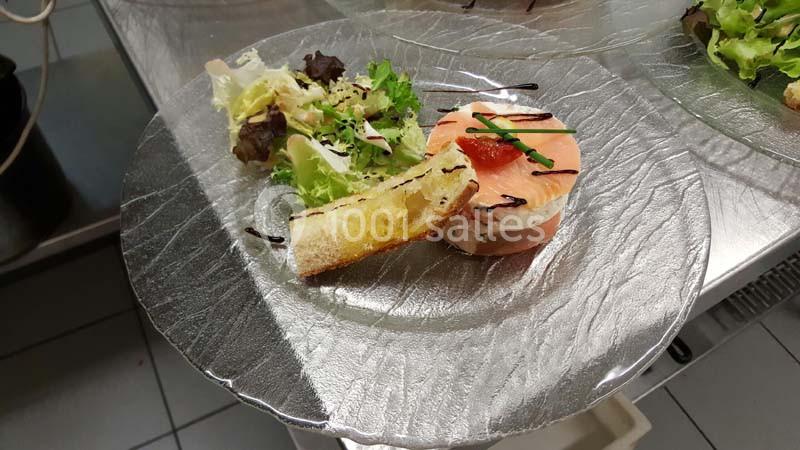 Assiette composée d'une tranche de saumon fumé, d'une salade verte, d'une tartine grillée et d'une sauce décorative.