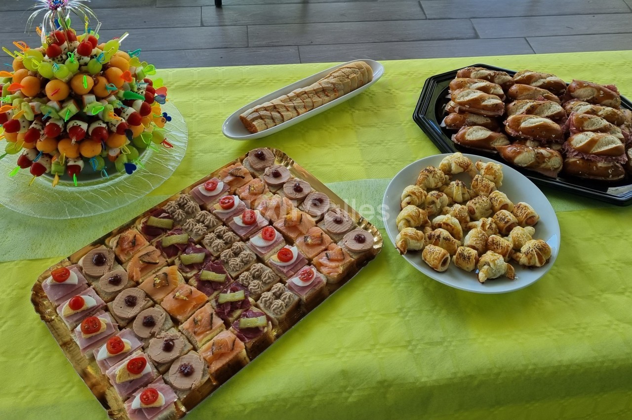 Plateau de pâtisseries variées, brochettes de fruits et viennoiseries disposés sur une nappe jaune.