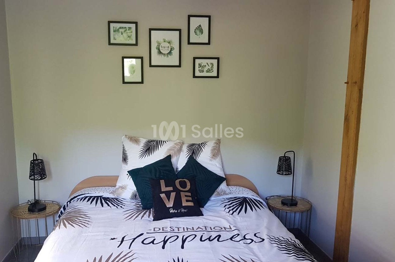 Lit double avec housse de couette à motifs tropicaux, coussins décoratifs et cadres muraux dans une chambre lumineuse.