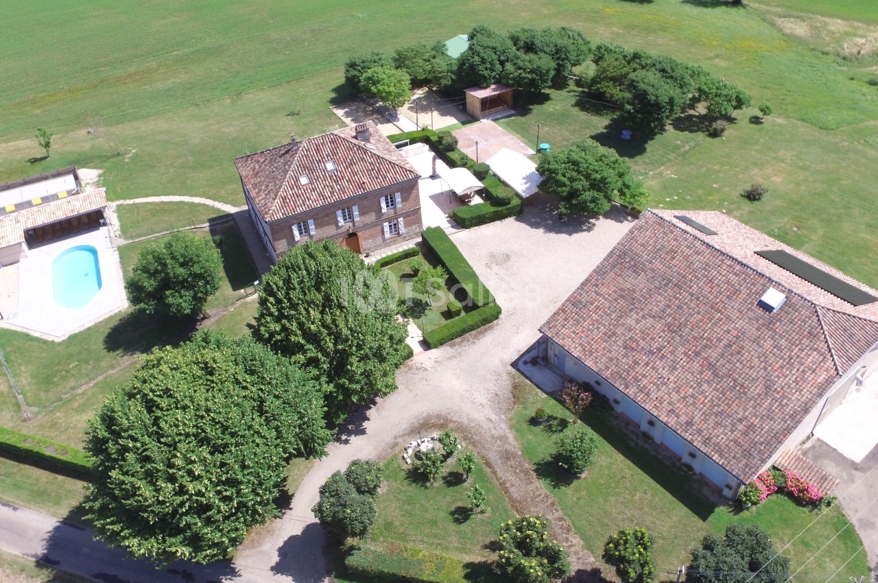 Vue aérienne d'une propriété rurale avec maison principale, dépendances, piscine et espaces verts environnants.