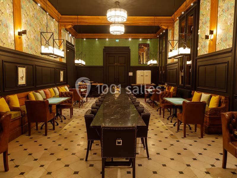 Salle élégante avec une longue table centrale, chaises en cuir, murs décorés et éclairage suspendu chaleureux.
