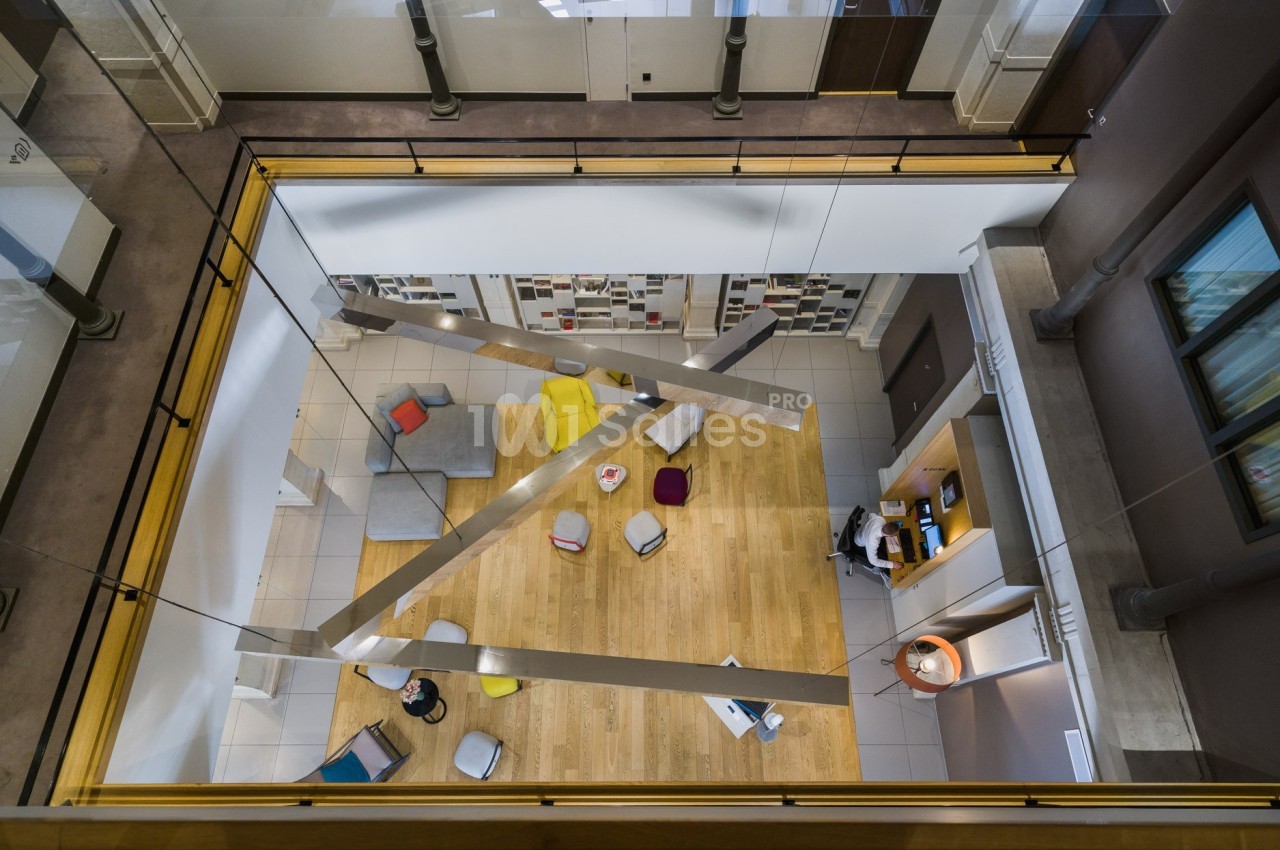 Vue plongeante sur un espace de détente moderne avec canapés, coussins colorés et étagères murales.