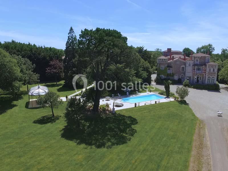 Vue aérienne d'un domaine avec un grand jardin, une piscine, une tente et un bâtiment de style ancien en arrière-plan.