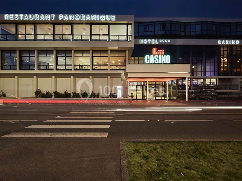 Façade d'un bâtiment moderne abritant un restaurant panoramique, un hôtel et un casino, vue de nuit.