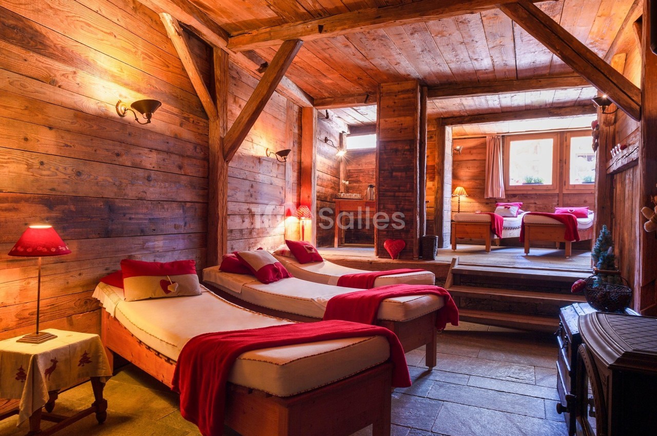 Chambre en bois chaleureux avec lits simples, couvertures rouges, lumière naturelle et décoration alpine.