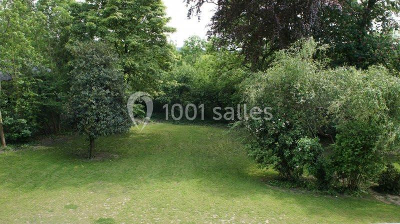 Pelouse entourée d'arbres et de buissons dans un espace verdoyant.