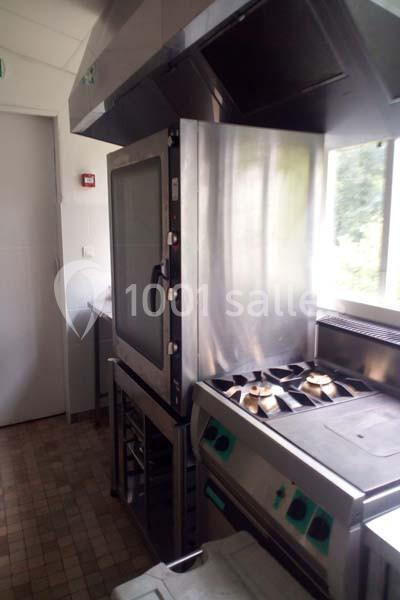 Cuisine professionnelle équipée d'un four inox à porte vitrée et d'une cuisinière à gaz avec plusieurs brûleurs.