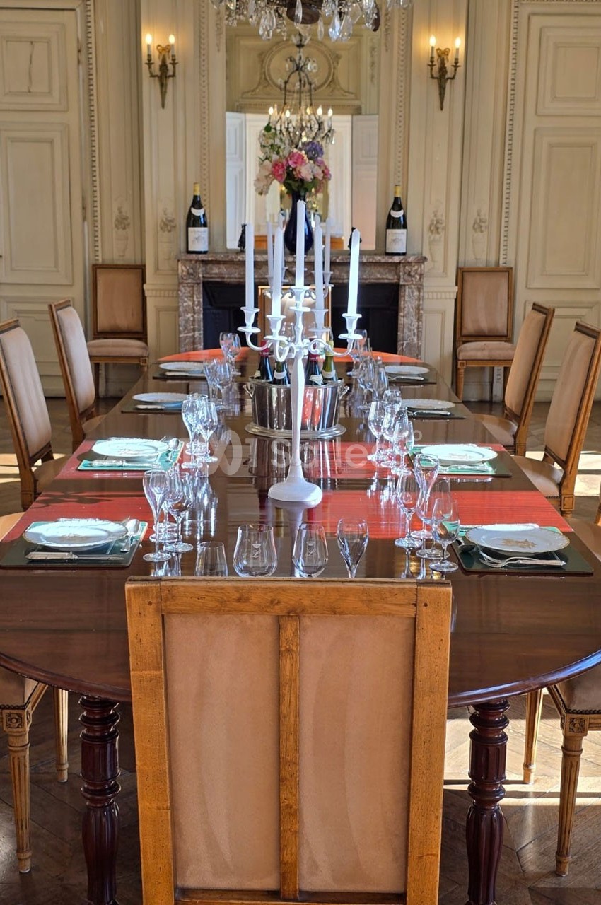 Table élégamment dressée avec chandeliers, verres et assiettes, dans une salle à manger au décor classique et raffiné.