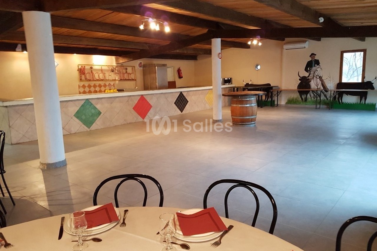 Salle de réception avec tables dressées, comptoir décoré de losanges colorés et fresque murale représentant un cavalier.