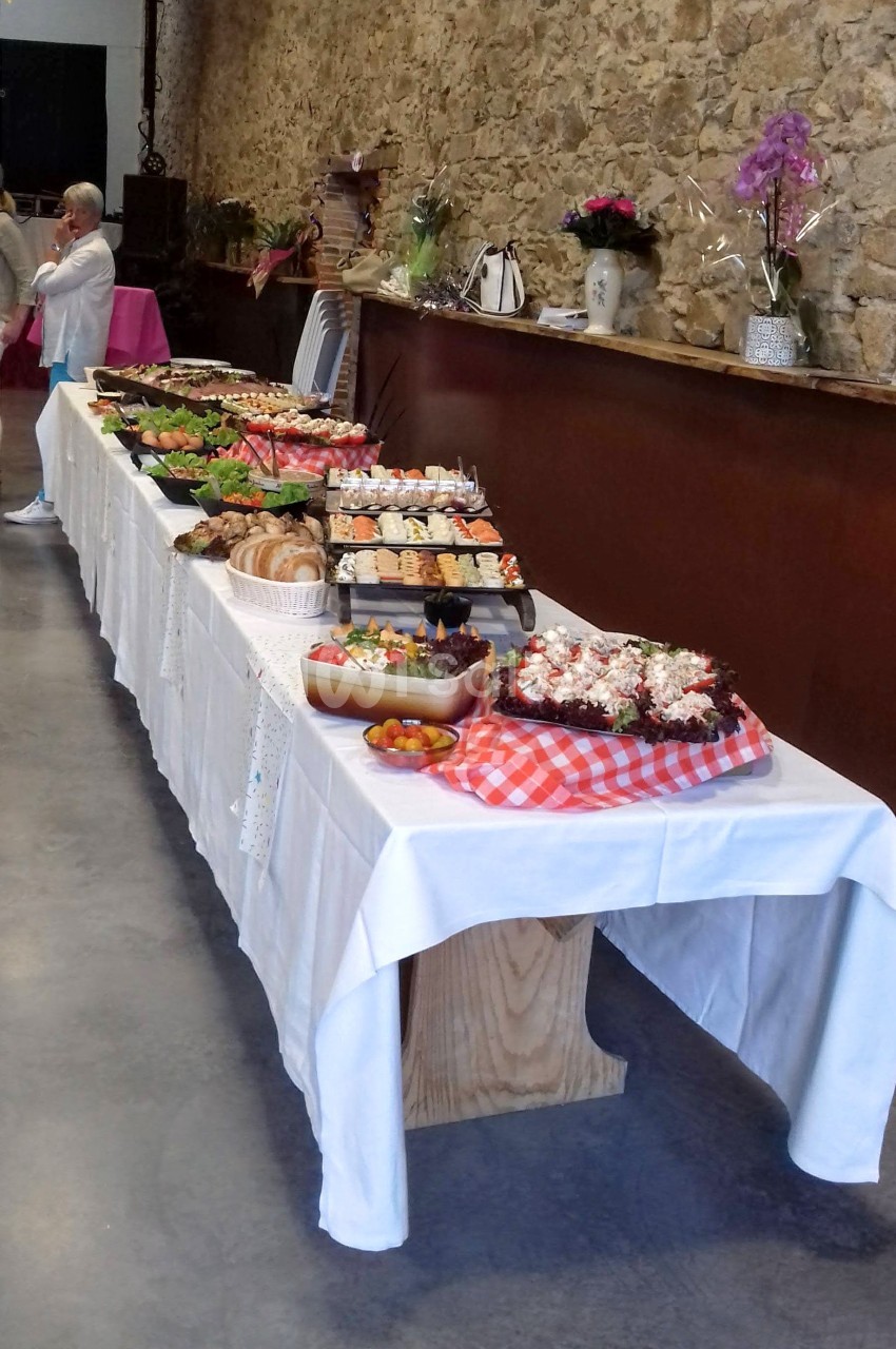 Buffet varié disposé sur une longue table avec plats sucrés et salés dans une salle aux murs en pierre.