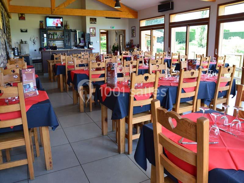 Salle de restaurant lumineuse avec des tables dressées, nappes rouges et noires, et chaises en bois décorées de cœurs.