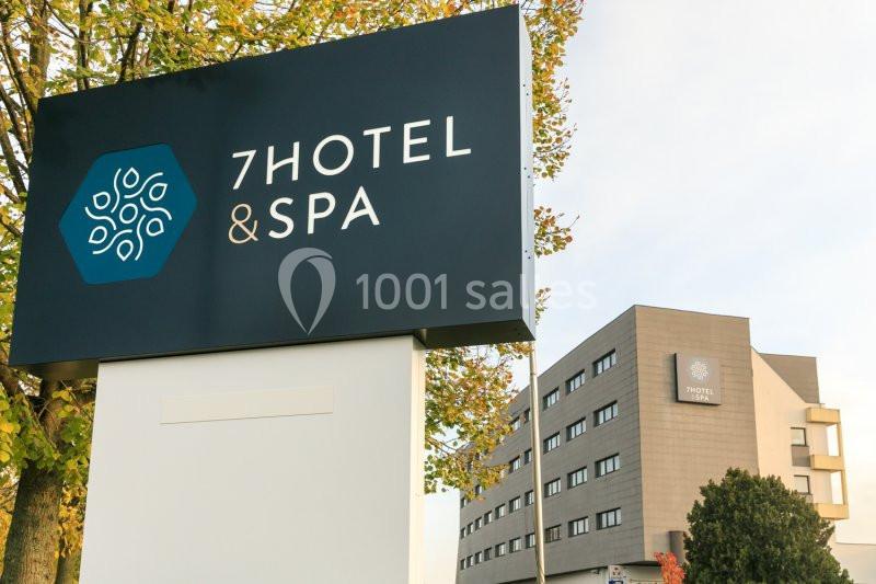 Panneau indiquant ’7Hotel & Spa’ devant un bâtiment moderne entouré d'arbres.