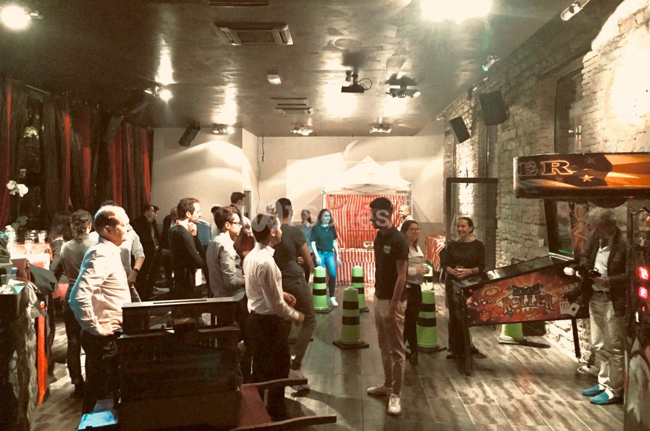 Des personnes participent à un événement dans une salle avec des jeux d'arcade et une ambiance tamisée.