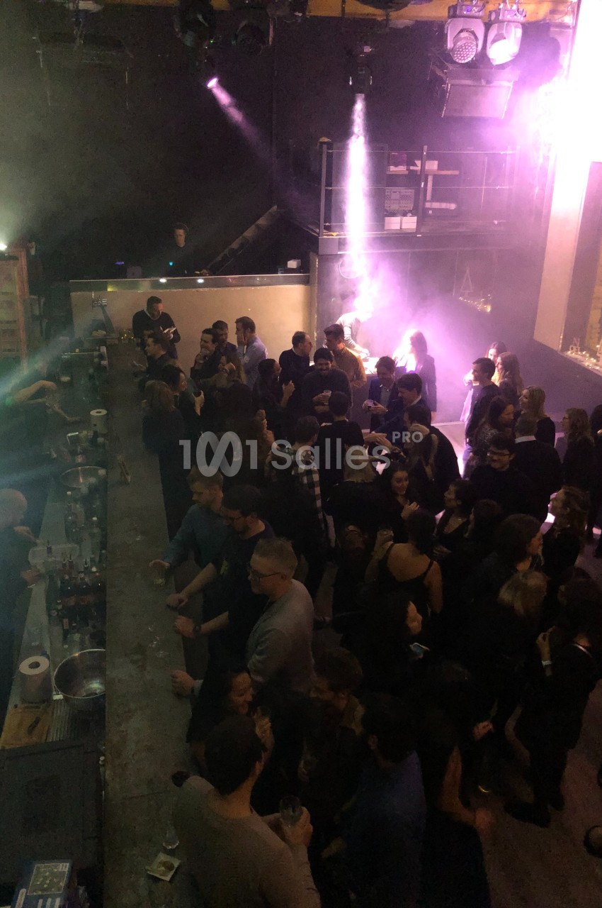 Vue plongeante d'une foule dans un bar ou une discothèque, avec éclairage tamisé et ambiance festive.