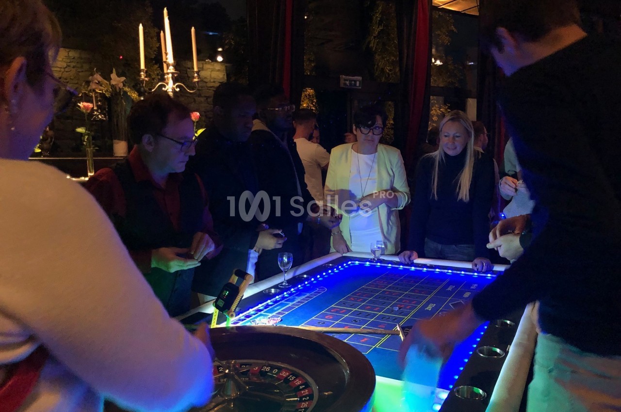 Des personnes jouent autour d'une table de roulette éclairée dans une ambiance tamisée.
