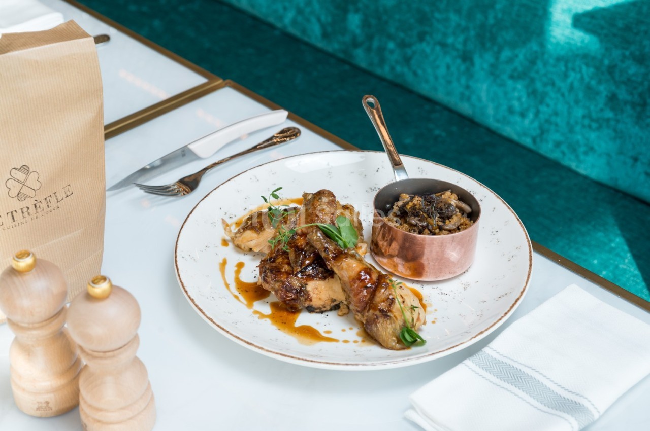 Assiette de volaille rôtie avec sauce, accompagnée d'une garniture dans une petite casserole en cuivre, sur une table…