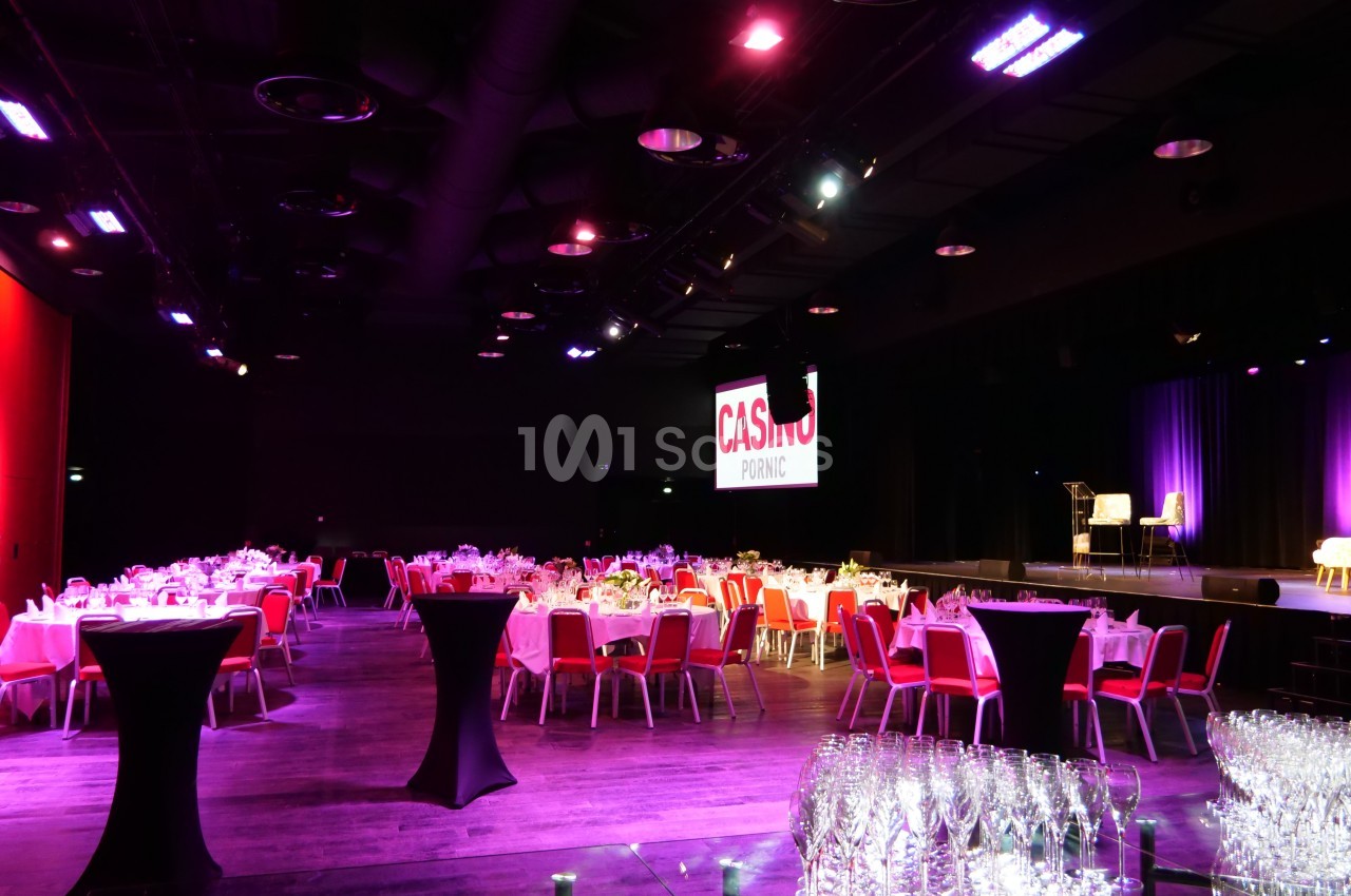 Salle de réception avec tables dressées, éclairage tamisé et écran affichant ’Casino Pornic’ en arrière-plan.