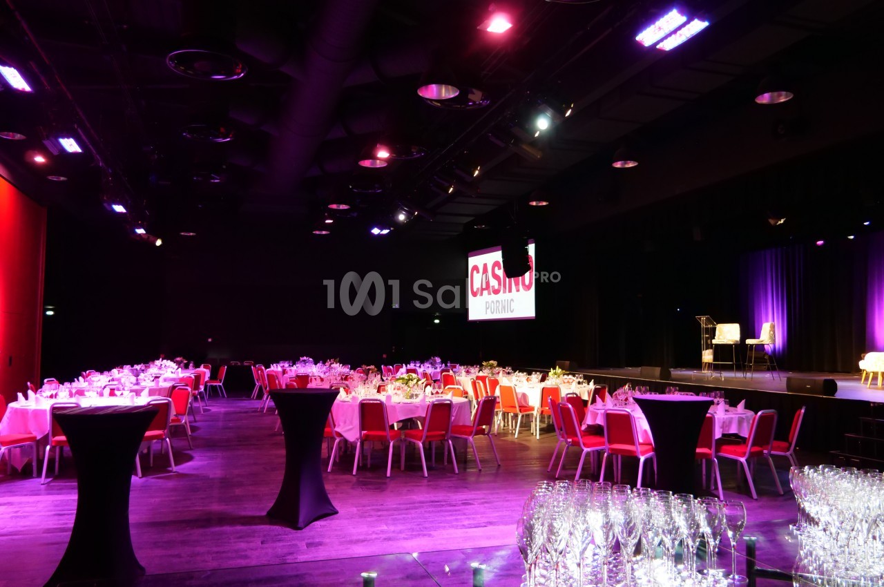 Salle de réception avec tables dressées, éclairage tamisé et écran affichant ’Casino Pornic’ en arrière-plan.