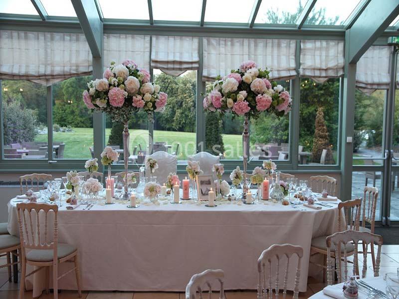 Table de réception élégamment décorée avec des fleurs roses et blanches, bougies et vaisselle raffinée, dans une salle…