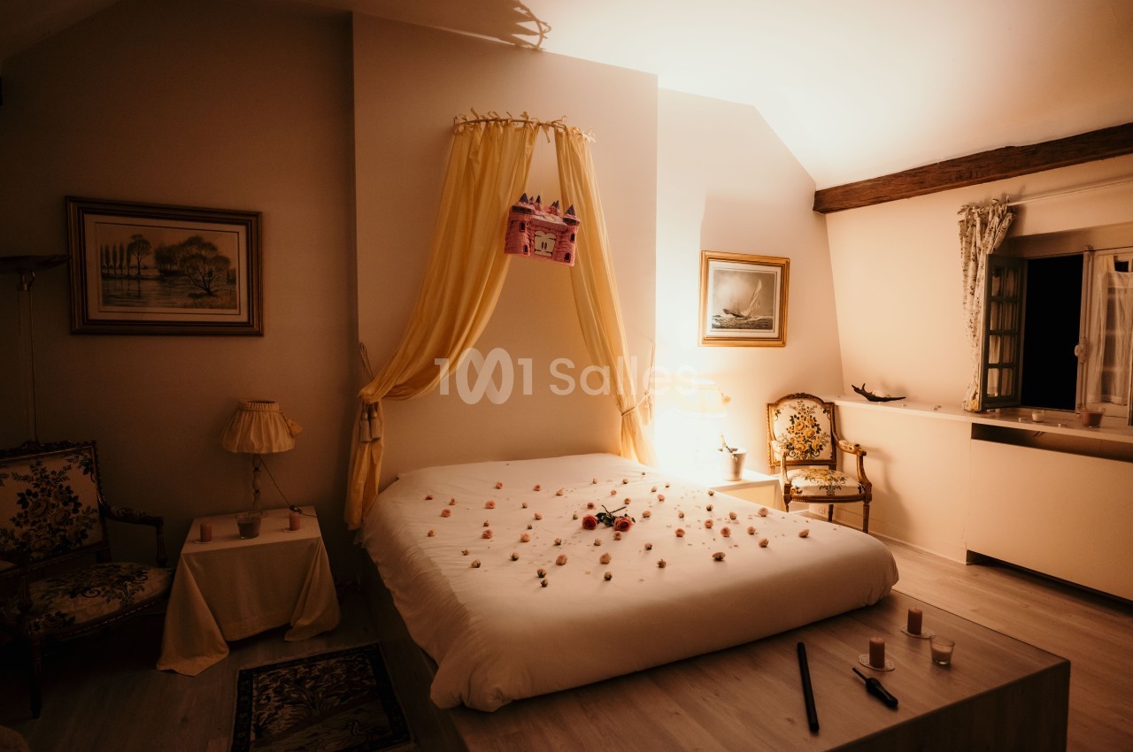 Lit double décoré de pétales de fleurs dans une chambre chaleureuse avec lumière tamisée et mobilier classique.