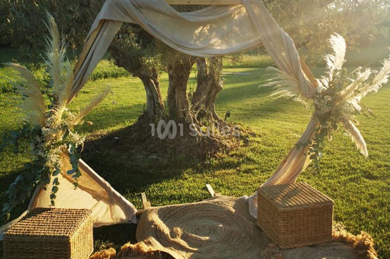 Arche décorative en tissu beige avec ornements végétaux, installée sur une pelouse au coucher du soleil.