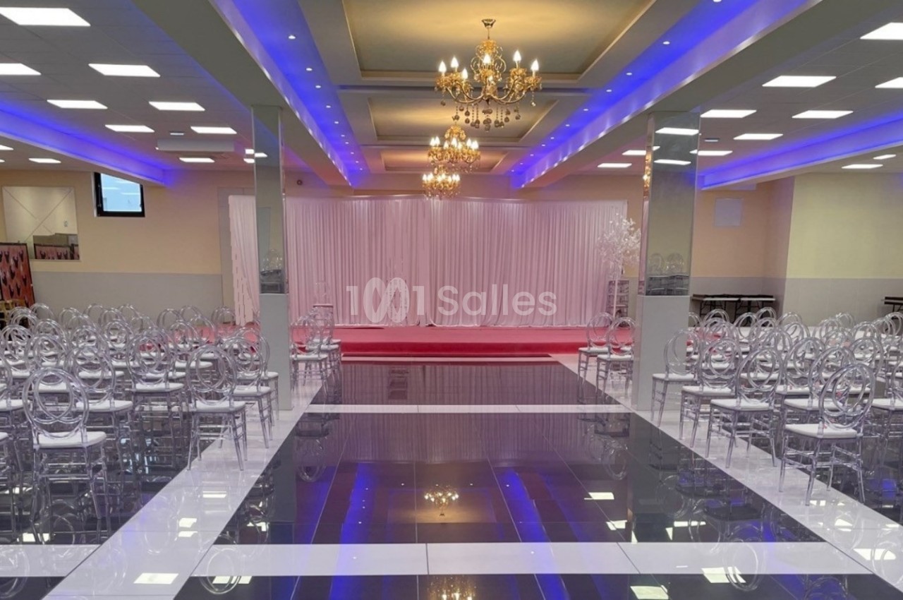 Salle de réception avec chaises transparentes alignées, lustres suspendus et éclairage coloré au plafond.