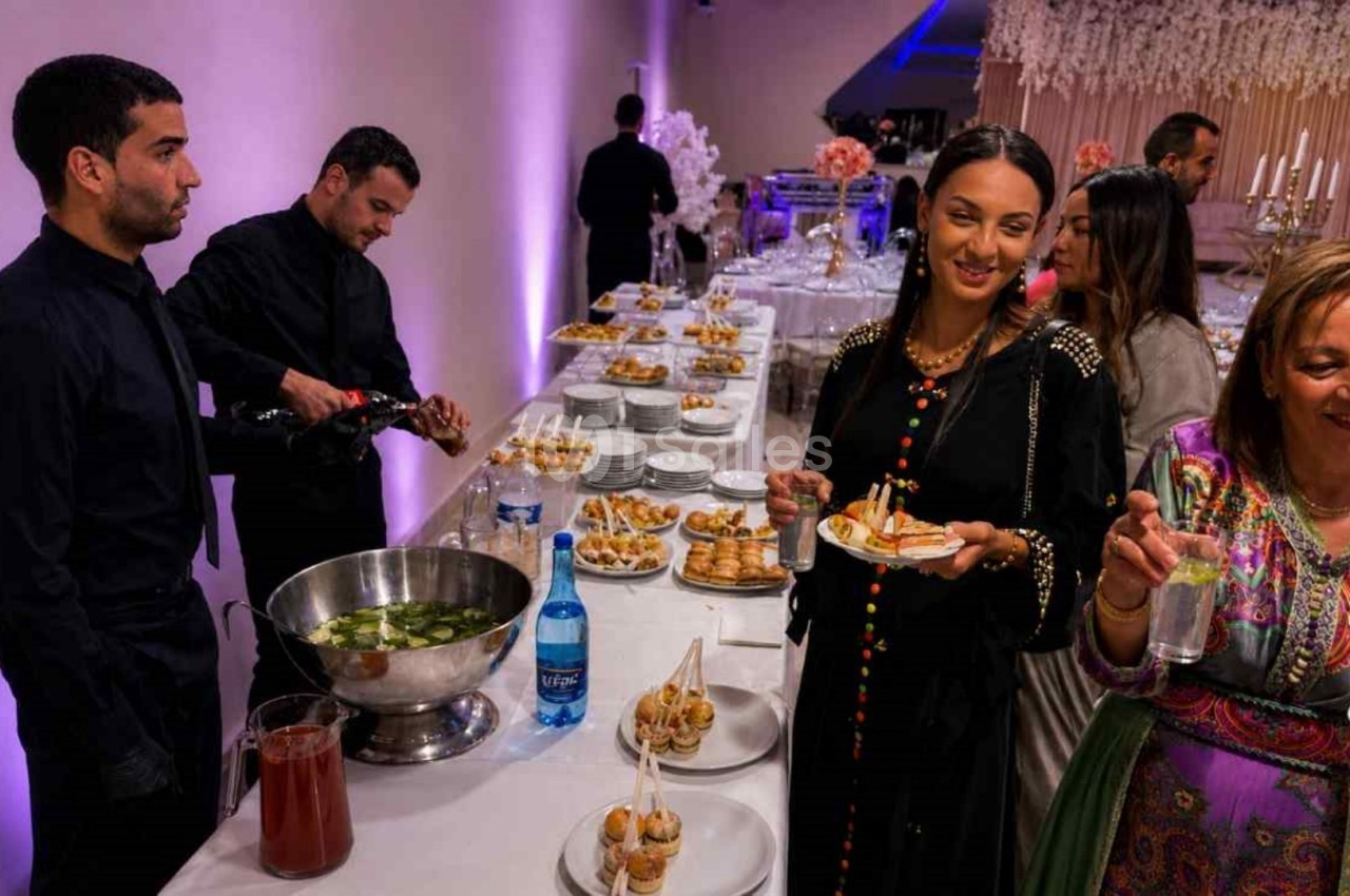Des convives se servent à un buffet lors d'un événement, avec des serveurs en arrière-plan.