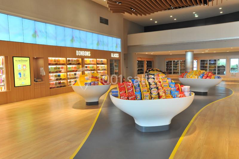 Rayons d'un magasin lumineux avec des présentoirs remplis de bonbons et snacks colorés.