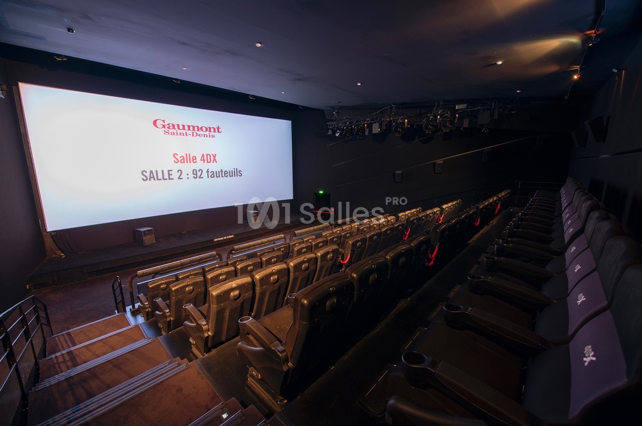 Salle de cinéma vide avec des sièges inclinables et un écran affichant des informations sur la salle 4DX.