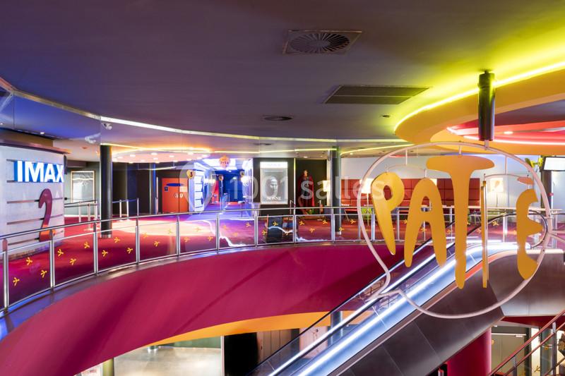 Escalier coloré menant à un cinéma avec enseignes lumineuses et affiches de films visibles en arrière-plan.