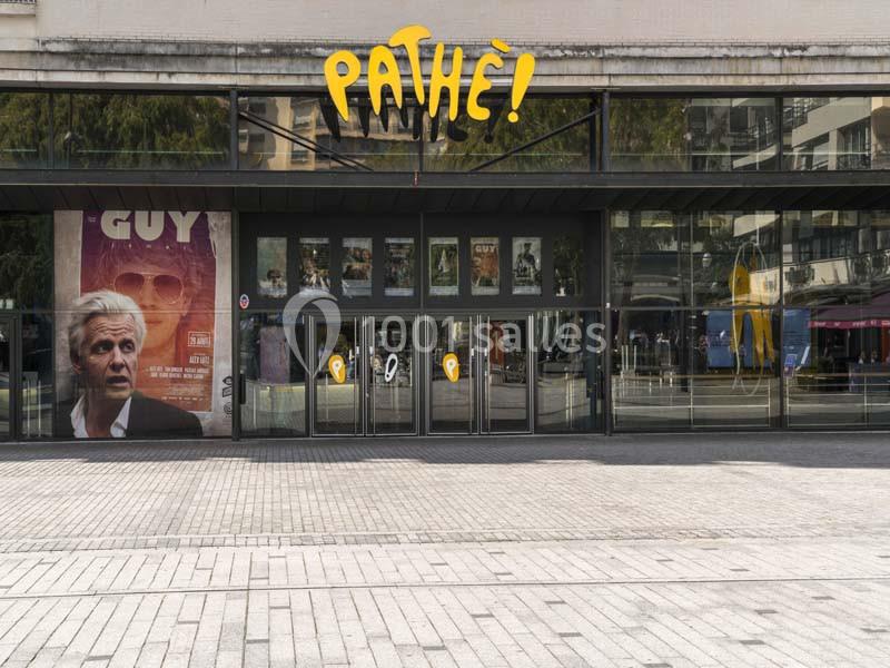 Façade d'un cinéma Pathé avec affiches de films et entrée vitrée donnant sur une place pavée.