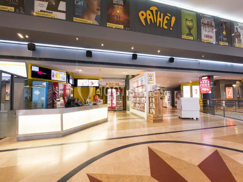 Hall d'entrée lumineux d'un cinéma Pathé avec comptoirs de billetterie, affiches de films et espace de confiserie.