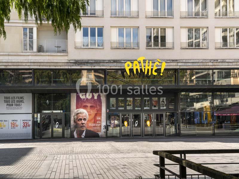 Façade d'un cinéma Pathé avec une affiche du film ’Guy’ et des vitrines donnant sur une place pavée.