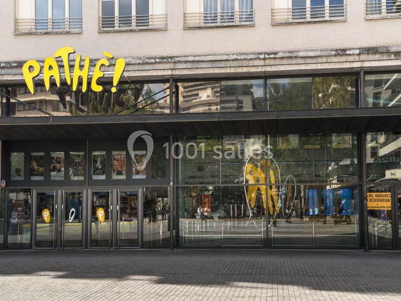 Façade vitrée d'un cinéma Pathé avec affiches de films visibles à l'intérieur et trottoir au premier plan.
