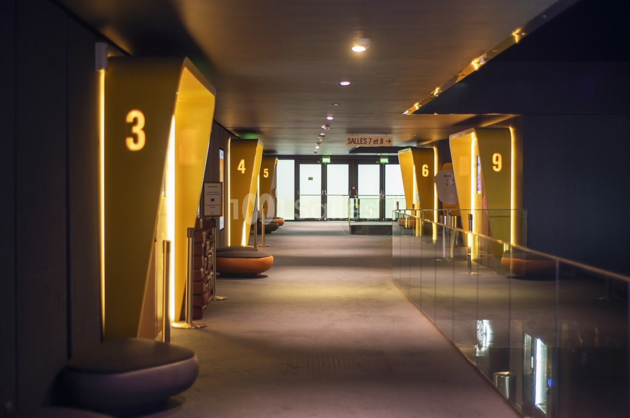 Couloir moderne avec éclairage tamisé, numéros lumineux sur les alcôves et portes vitrées au fond.