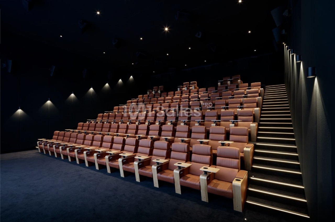 Salle de cinéma moderne avec sièges en cuir marron disposés en gradins et éclairage tamisé.