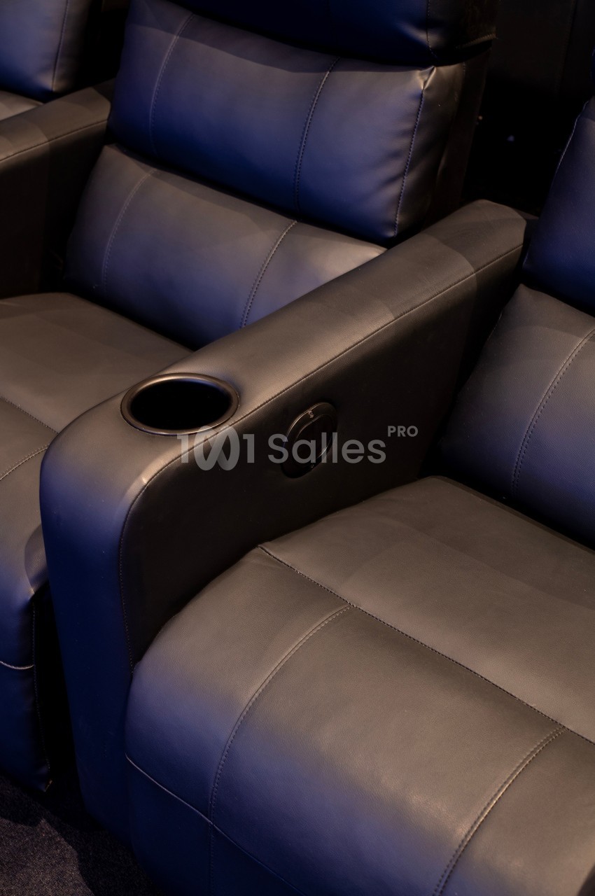 Fauteuils de cinéma en cuir noir avec accoudoirs équipés de porte-gobelets intégrés.