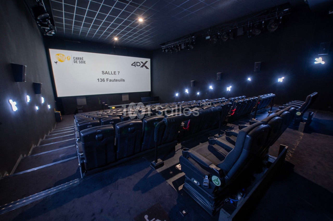 Salle de cinéma moderne avec sièges inclinables, éclairage tamisé et écran affichant des informations sur la salle.