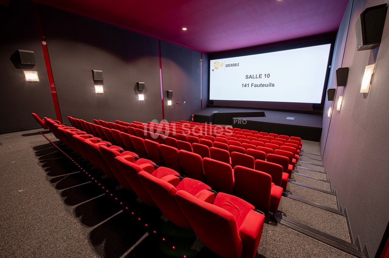 Salle de cinéma moderne avec rangées de fauteuils rouges et écran affichant ’Salle 10 - 141 fauteuils’.