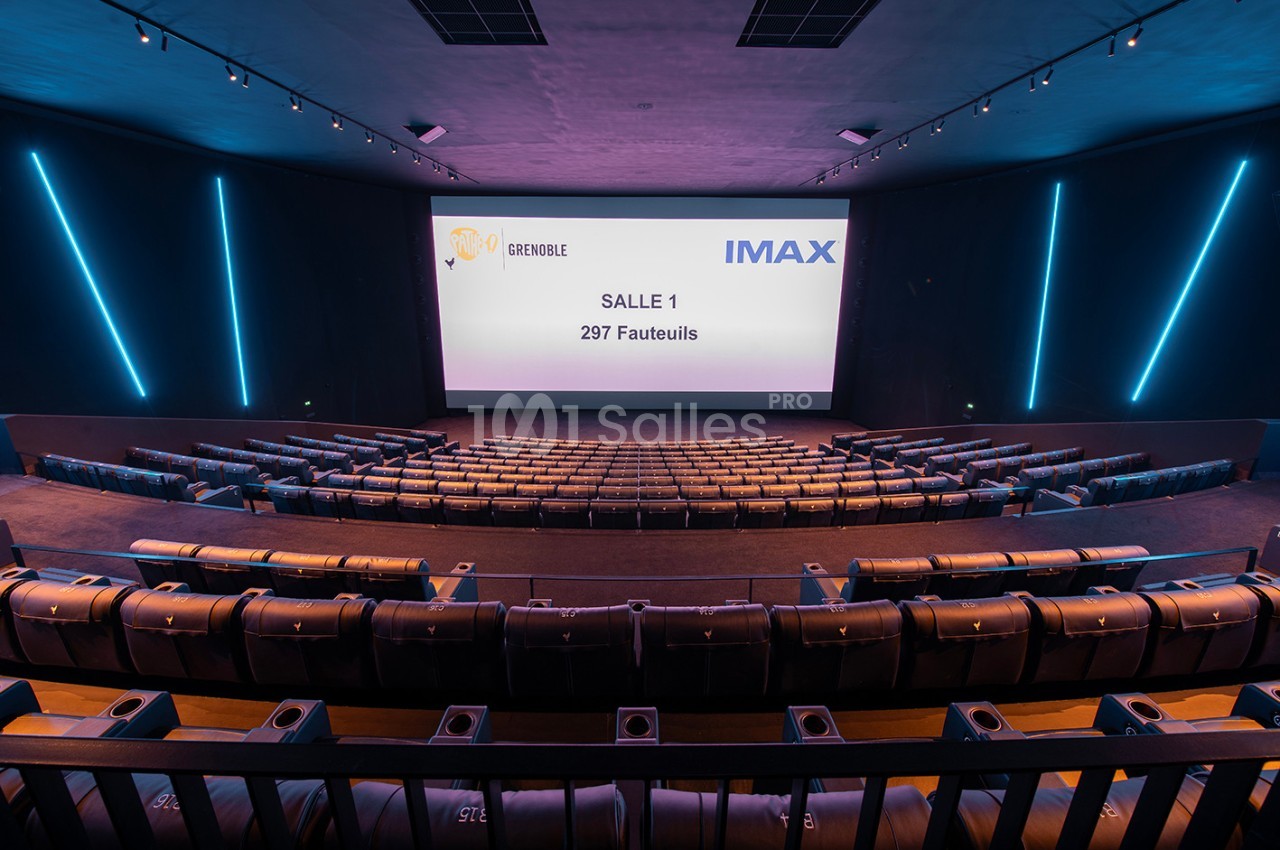 Salle de cinéma IMAX vide avec écran affichant ’Salle 1, 297 fauteuils’, rangées de sièges et éclairage moderne.